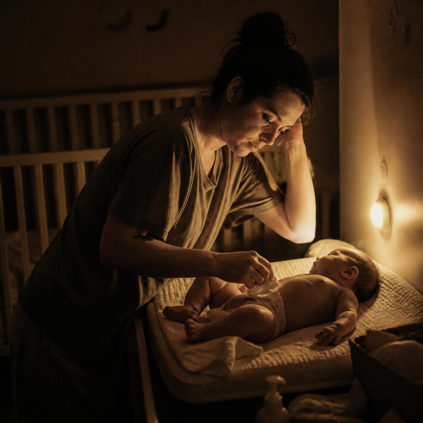 Mãe exausta trocando fralda do bebê na madrugada